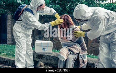 Ärzte im Schutz passen zur Pflege einer Frau Stockfoto