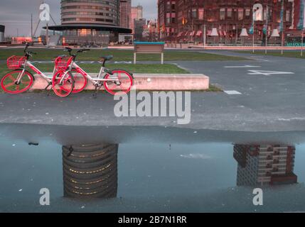 Rotterdam, Niederlande - 12. Februar 2019: Hotel New York, zwei vor dem Hotel geparkte rote Fahrräder, das Hotel und die Fahrräder, die sich darin widerspiegeln Stockfoto
