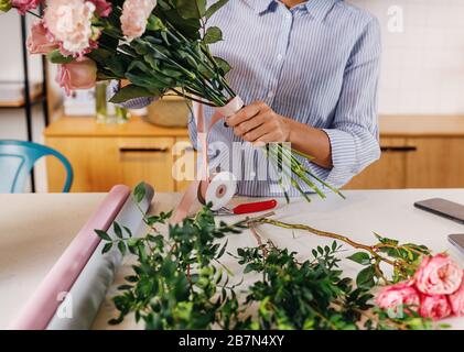 Die Hände der Frau, die einen Blumenstrauß hält, der Blumen mit Band schmückt Stockfoto
