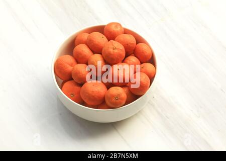Schüssel mit Mandarinorangen in weißer Schüssel auf der Marmorkonteroberseite Stockfoto