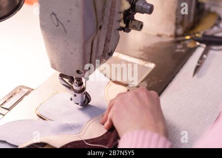 Näherin näht Schuhdetails, die Schuhe machen. Folge der Arbeit im Studio - der Prozess des Schneiderns, Detail-Nahaufnahme - die Maschine, der Faden, der Stoff, die ne Stockfoto