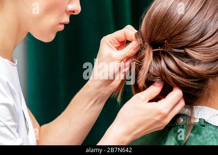 Die Hände machen Haarstyling auf den Haaren der Frau aus der Nähe. Stockfoto