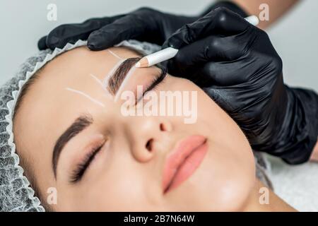 Markup mit Bleistift an den Augenbrauen der yong-frau während der dauerhaften Make-up. Stockfoto