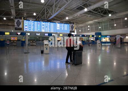 Athen Griechenland, 3. März 2020. Flughafenterminalgebäude innen. Ein Reisender in einer leeren Check-in-Theke in Coronavirus Tagen Stockfoto