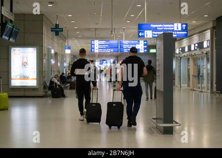 Athen Griechenland, 3. März 2020. Flughafenterminalgebäude innen. Rückansicht von Reisenden Personen mit Gepäck und blauen Hinweisschildern. Coronaviru Stockfoto