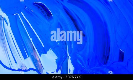 Abstrakter Hintergrund von verschütteter blauer Farbe mit Eimern auf schwarzem Hintergrund. Blaue Farbe gießt auf schwarzem Grund. Verwenden Sie es für einen Künstler oder Stockfoto