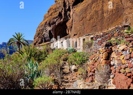 Verlassene Häuser unter Felswand, Tacalcuse, in der Nähe von San Sebastian, La Gomera, Kanarische Inseln, Spanien Stockfoto