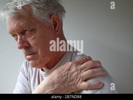Älterer Mann mit einer schmerzhaften Schulter bei natürlichem Licht Stockfoto