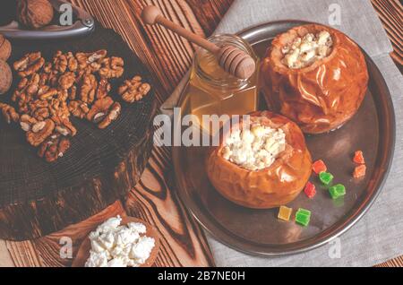Gesundes Essen. Bratäpfel mit Quark und Muttern liegen in einem schwarzen Auflaufform auf einem Holztisch Stockfoto