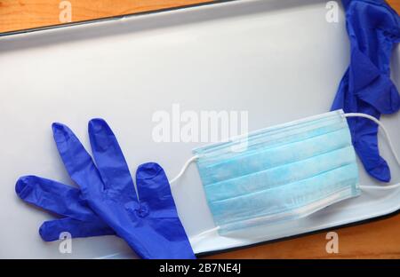 Weißes Tablett mit Kunststoffhandschuhen und Gesichtsmaske mit Kopierbereich Stockfoto