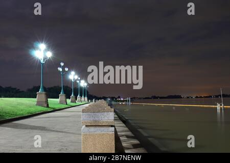 Das Licht von einem Lichtpfosten in der Nacht im Park: Am Riverwalk, Beleuchtung, Sitzgelegenheiten, abendliche Erholungslandschaft Stockfoto