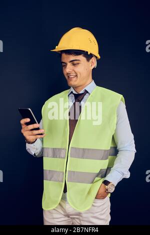 Junger Ingenieur mit Handy und Helm Stockfoto