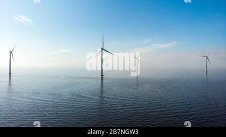 Windmühlenreihe im Meer am See Ijsselmeer Niederlande, Windmühlenfarm Flevoland für erneuerbare Energien Stockfoto