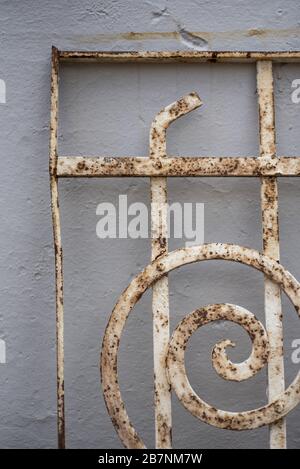 Alter weißer rostiger Eisenzaun gegen eine weiße Betonwand Stockfoto