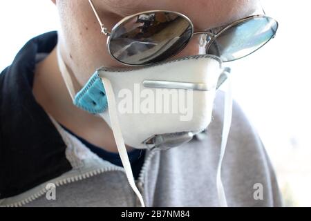 Der Mann in einem Atemschutzmaske und eine Brille blicken nach unten. Nahaufnahme Stockfoto