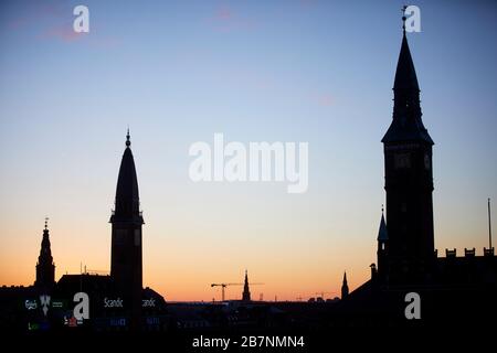 Kopenhagen, die Hauptstadt Dänemarks, der Uhrturm des Scandic Palace Hotels und der City-Hall-Uhrturm wurden bei Sonnenaufgang silhouettiert Stockfoto