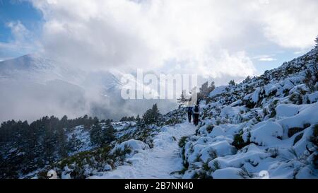 PEñALARA, SPANIEN - 17. November 2018: Ein Bild von einigen Frauen, die auf einem Weg in einer verschneiten Landschaft wandern. Stockfoto