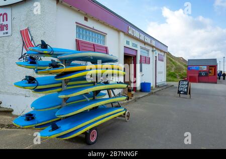 Surfschule an der Promenade in Saltburn an der Sea Surf Ausrüstung und Anzüge für Liegestuhl und Windpausen Stockfoto