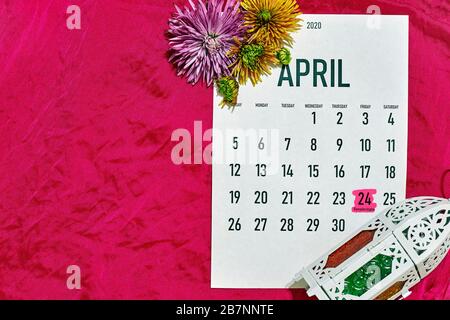 April monatlicher Kalender über den Hintergrund der roten Seidentextilien. Islamischer Ramadan Eid festlicher Hintergrund mit Frühlingsblumen und Laterne Stockfoto