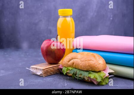 Schulessen, Bücher, Saft, rosafarbener Wecker, Schultafel für den Text mit Kreide. Schulpause. Freier Speicherplatz für Text. Horizontales Format Stockfoto