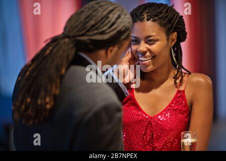 Der junge Mann berührt sanft die Wange der lächelnden jungen Frau, mit der er an einer Bar flirtet. Stockfoto