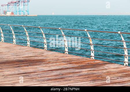 Leere Promenade an einem sonnigen Tag. Metallgeländer und Holzbalken einer Terrasse am Meer. Langeron Stadtstrand an einem sonnigen Frühlingmorgen. Stockfoto