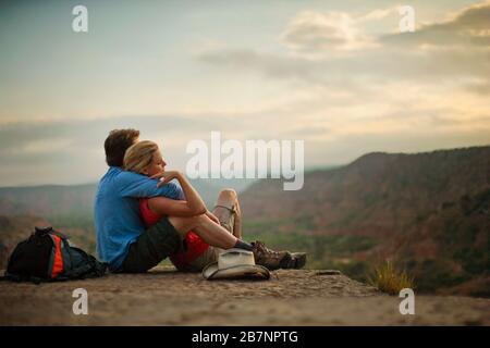 Liebevoll junge Paare machen eine Pause vom Wandern und bewundern die Aussicht, während sie in die Arme der anderen eingewickelt sind. Stockfoto