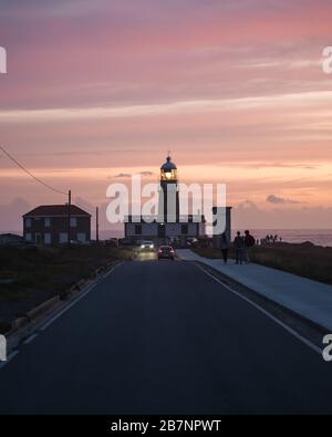 Schöner Leuchtturm am Ende der langen Straße bei Sonnenuntergang in Galicien, Spanien Stockfoto