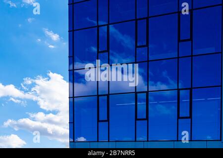 Abstrakter Hintergrund für Bürogebäude. Wolken und Himmel spiegelten sich in Fenstern des modernen Bürogebäudes wider. Wolkenkratzer in der Stadt Stockfoto