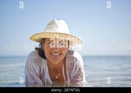 Porträt einer Frau, die im Wasser an einem Strand liegt. Stockfoto