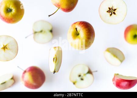 In Scheiben geschnittene rote Äpfel fliegen über weißem Hintergrund, Levitationseffekt Stockfoto