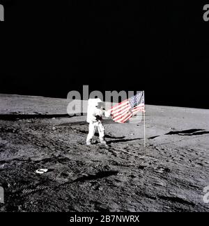 Apollo 12 - NASA, 1969. Während der ersten extravehikulären Aktivität gibt Astronaut Charles Conrad, Jr., Apollo 12-Kommandant, die Flagge der Vereinigten Staaten auf der Mondoberfläche frei. Stiefelabdrücke der Astronauten sind auch auf dem Bild zu sehen, 19. November 1969. Stockfoto