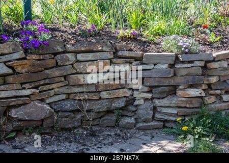 Trockensteinmauer aus Natursteinen im Garten Stockfoto