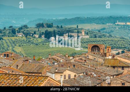 Dächer von San Gimignano, toskanische Landschaft mit sanften Hügeln und Santa Maria Assunta a Monte Oliveto Minore aus Parco della Rocca, San Gimignano. Stockfoto