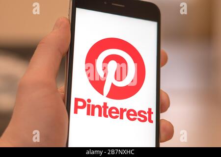 Schwarzes Telefon mit Logo von Social Media Pinterest auf dem Bildschirm. Symbol für soziale Medien. Hand mit Telefon. Kann als Illustration für Marketing oder Business verwendet werden Stockfoto