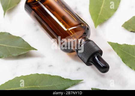 Lorbeer ätherisches Öl auf Marmortisch. Bay Oil auf Glasflasche mit Tropper. Laurus nobilis Stockfoto