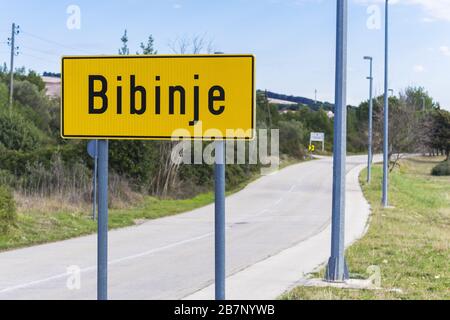 Gelbes Straßenschild zeigt den Beginn des Dorfes Bibinje In Kroatien Stockfoto