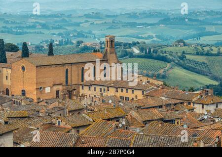 Chiesa di Sant'Agostino und die Dächer des historischen Zentrums von San Gimignano von der Rocca di Montestaffoli im Parco della Rocca aus gesehen. Stockfoto