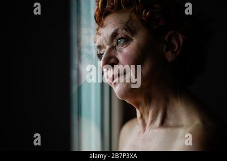 Frau am Fenster, die über das Leben nachdenkt Stockfoto