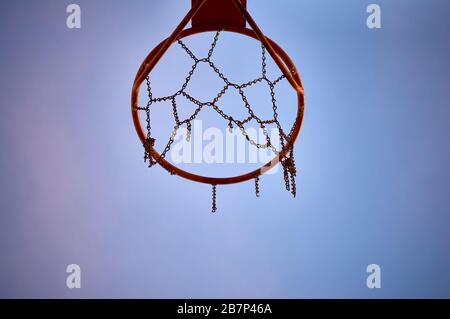 Isoliertes Detail des Hops eines orangefarbenen Basketballnetzes mit einer Kette nach Netz und beschädigt Stockfoto