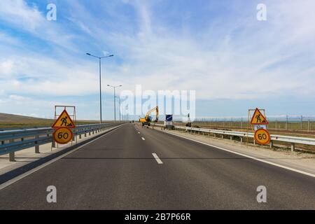 Anzeichen für Geschwindigkeitsbegrenzung an der Stelle der Straßenverengung wegen der Reparaturarbeiten. Die Aufschrift auf Russisch: "Achtung! Reparaturarbeiten' Stockfoto
