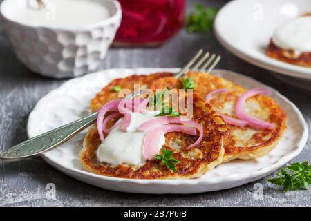 Frühstück aus traditionellen Boxsäcken oder Latkes, serviert mit eingelegten Zwiebeln und saurer Sahne. Stockfoto