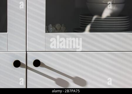 Harte und weiche Schatten auf einem weißen Schrank mit Utensilien. Stockfoto