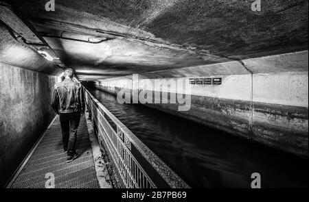 Anderlecht, Brüssel / Belgien - 07 16 2019: Der überdachte Fluss La Senne, mit einem Metallpfad am Kanalmuseum und einem Mann beim Spazierengehen Stockfoto