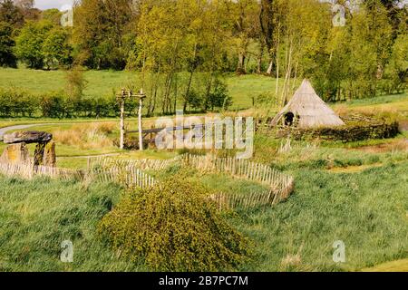Traditionelles Gehäuse mit Reetdach des alten Hauses, umgeben von Palisade und Hecke. Grüne Felder und Wald im Hintergrund Stockfoto
