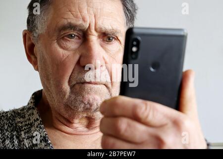 Älterer Mann mit Smartphone, Handy in männlichen Händen nah dran. Konzept der Online-Kommunikation im Ruhestand, sms, soziale Medien, schlechte Nachrichten Stockfoto