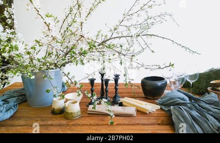 Verschiedene bunte Blumen und grüne Pflanzen in Eimern auf Holztisch in hellweißem Raum Stockfoto