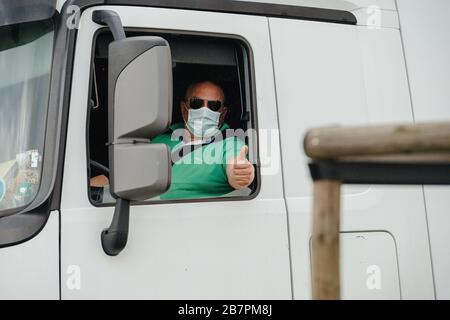 Kehl, Deutschland - 16. März 2020: Lkw-Fahrer in Mercedes-Benz Actros mit Schutzmaske zeigt OK-Zeichen beim Grenzübergang Strasbourg Kehl Krisenmaßnahmen gegen das neuartige Coronavirus Stockfoto