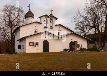 Eine der weißen Steinkirchen der Stadt Pskov (Russland) vor dem Hintergrund der Festungsmauer und stürmischen Himmel Stockfoto