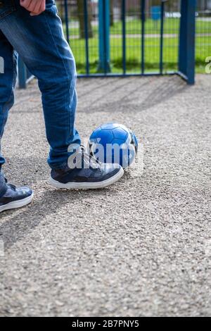Teenager treten einen Fußball in Richtung eines Ziels in einem Spielbereich im Freien Stockfoto